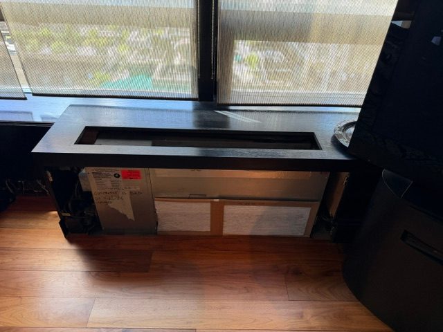 A dark wood enclosure running along a window sill.